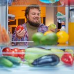 Happy man choosing what to eat late at night.