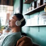 Young Asian man with eyes closed, enjoying meditating with his headphones