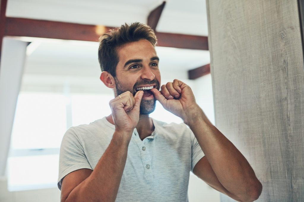 Man flossing his teeth to keep his oral microbiome healthy