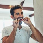 Man flossing his teeth to keep his oral microbiome healthy